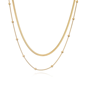 Close-up of double-layer gold snake chain and beaded necklace with polished finish