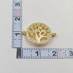 Detailed view of golden Tree of Life charm with micro-paved zircons and measuring tape