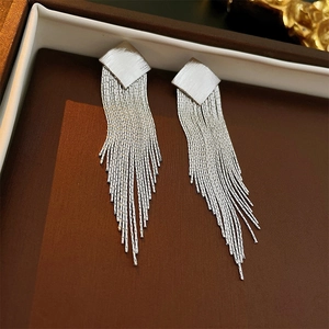 Macro detail of geometric diamond shape metal tassel earrings in a jewelry box