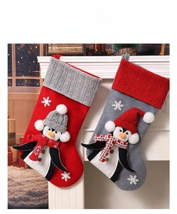 Close-up of grey and red Christmas stockings with 3D penguins on a white fireplace