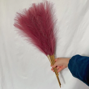 Close-up of hand holding a 55cm deep pink artificial pampas grass bouquet for boho decor