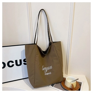 Detail of large brown tote bag featuring leopard print strap and beyou merci lettering