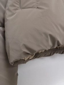 Detail of khaki puffer jacket showing elastic windproof cuffs and high-density fabric
