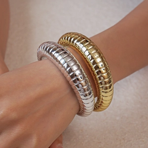 Detailed macro view of chunky ribbed gold and silver plated bangles on wrist