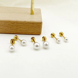 Detailed macro view of three sizes of pearl stud earrings with golden metal bases