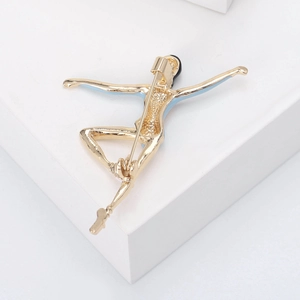 Close-up of golden ballet dancer brooch showing blue enamel details and pin fastener