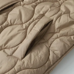 Detailed view of quilted diamond patterns and side pockets on a beige winter coat