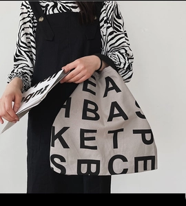 Close-up of a minimalist cream canvas tote bag featuring black block letter patterns