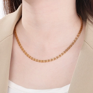 Close-up of a gold-plated musical note chain necklace worn by a model on the neck