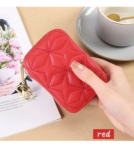 Macro view of a red quilted star pattern mini lipstick bag with a gold keychain accessory