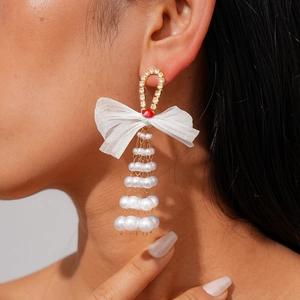 Close-up of model wearing long bow tassel earrings with pearls and crystals