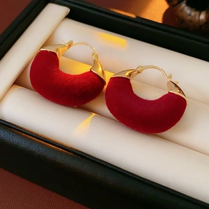 Detail of red velvet U-shaped earrings in a black jewelry box with gold metal clasps