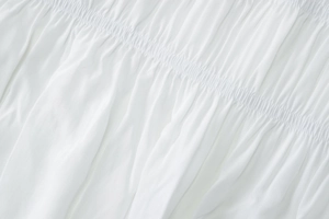 Gros plan sur le tissu froncé blanc texturé avec plis ondulés délicats pour robe