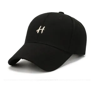 Detailed close-up of embroidered H letter on black cotton baseball cap with curved brim