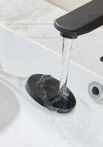 Close-up of long-handled bath brush with black bamboo charcoal sponge rinsing under water