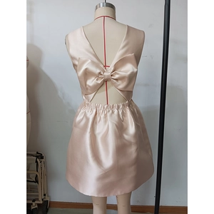 Détail d'une robe en satin champagne avec un grand nœud papillon et dos nu élégant