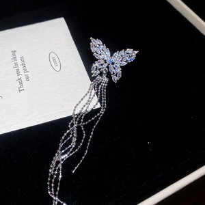 Close-up of silver zircon butterfly earring with long tassels on black velvet