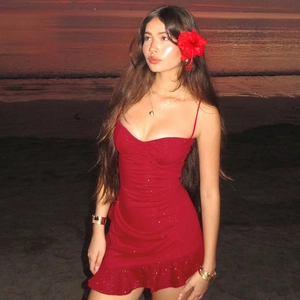 Close-up of red sequined bodycon mini dress with ruffled hem at sunset beach