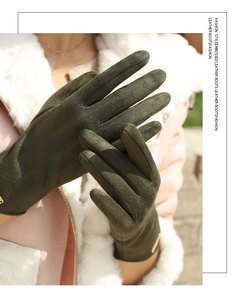 Close-up of deep green suede winter gloves featuring elegant gold metal logo hardware