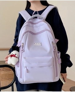 Detail of purple minimalist nylon backpack with a white plush keychain and metal zipper