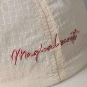 Detail of Magical Words pink embroidery on beige checkered quick-dry baseball cap