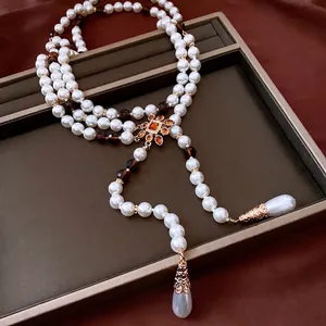 Vintage layered pearl necklace with floral pendant and amber beads on velvet background