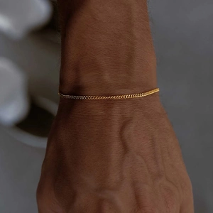 Close-up of a minimalist golden curb chain bracelet on a wrist with refined metallic shine
