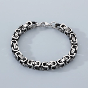 Detail of silver stainless steel curb chain bracelet with lobster clasp and twill pattern