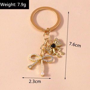 Detailed view of pearl and rhinestone bow keychain with dimensions 7.6cm by 2.3cm