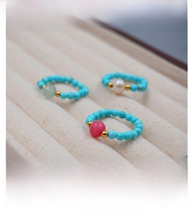 Detail view of turquoise beads and freshwater pearl elastic rings in a beige velvet tray