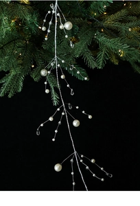 Detail of Christmas crystal bead garland with white pearls and silver wire on pine branch