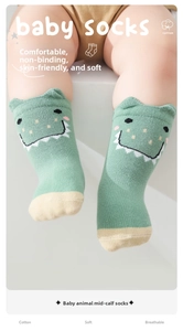 Close-up of green cotton baby socks with cute dinosaur patterns and yellow toe detail