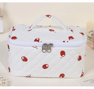 Detail of white quilted toiletry bag with red tomato print and sturdy top handle