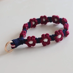 Detailed view of handmade woven floral phone strap in deep blue and wine red yarn