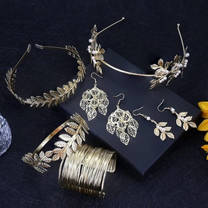 Detail view of gold leaf bridal jewelry set including headband, earrings, and cuff bracelet