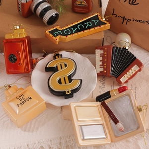 Ornamenti natalizi creativi a forma di profumo, rossetto e macchina fotografica