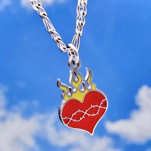 Hip-hop silver necklace with red heart and yellow flame pendant against a blue sky