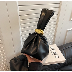 Close-up of black pleated bucket bag with large irregular gold metal buckle detail