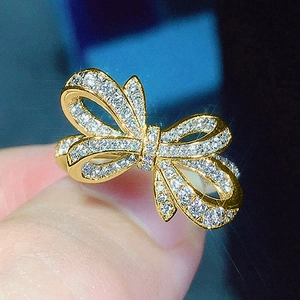 Gros plan d'une bague nœud dorée avec zircons montrant les détails fins du ruban