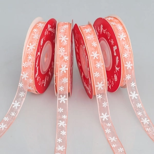 Detail view of four orange organza Christmas ribbons with white snowflake patterns