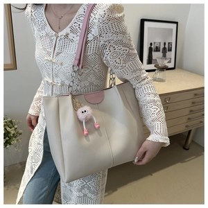 Dettaglio della borsa tote crema con manici rosa e catena d'argento su modella