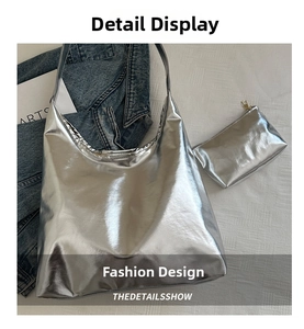 Detail of silver metallic tote bag with matching zipper pouch on textured fabric background