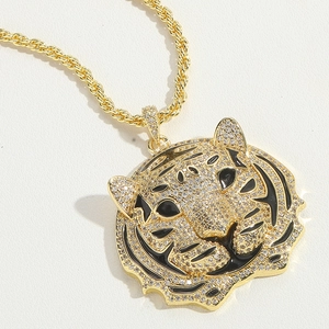 Close-up of golden tiger head pendant with inlaid crystals and black enamel on twisted chain