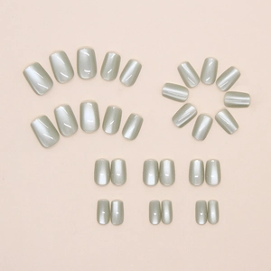 Flat lay of 24-piece short square-oval green cat-eye press-on nails set on pink background