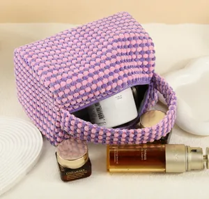 Detail of pink and purple checkered popcorn texture makeup bag with hand strap