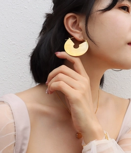 Close-up of golden brushed titanium geometric earrings worn by a model in detail