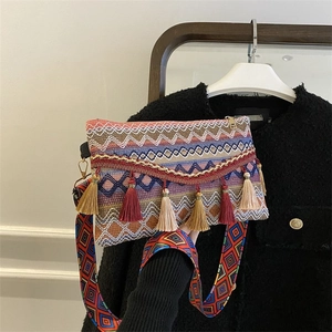 Detail of bohemian woven crossbody bag with colorful geometric patterns and long tassels