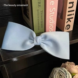 Detail of light blue satin bow hair clip with elegant silk texture and neat pleats