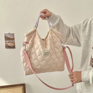 Close-up of pink quilted canvas bag with rabbit print and woven cylindrical handles
