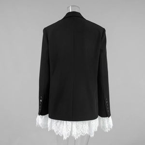 Detail of black blazer with white lace hem and sleeves featuring decorative buttons